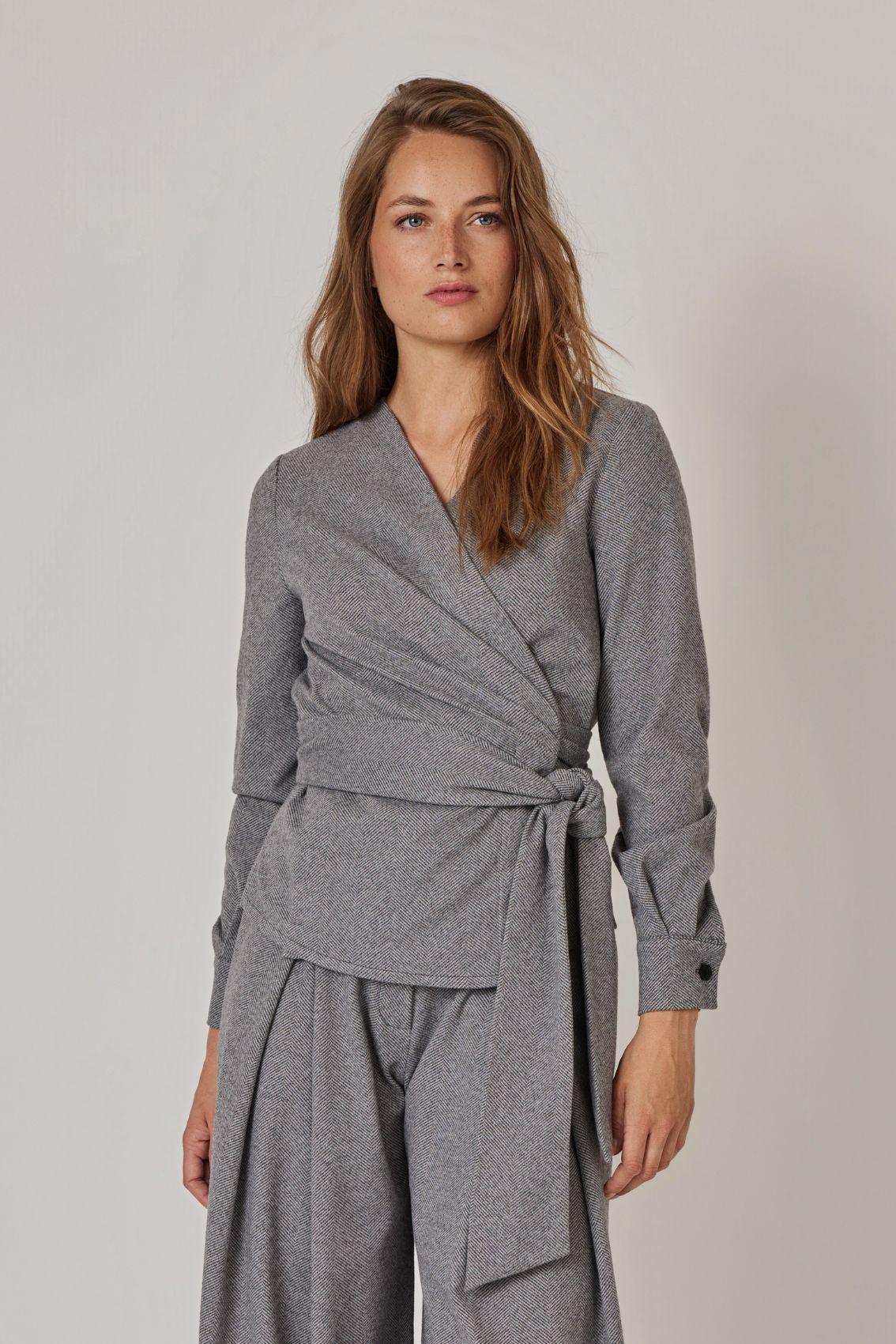 Model trägt Wickelbluse Grau meliert mit Bindegürtel zur passenden weiten Hose, Frontansicht.