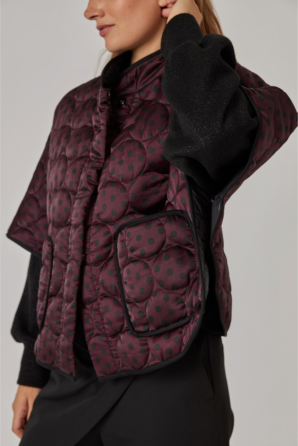 Detailansicht: aufgesetzte Tasche mit schwarzer Paspel und Kreissteppung am bordeauxfarbenen Cape.