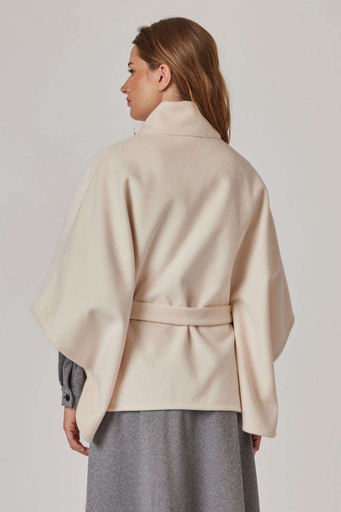 Model trägt Cape Creme, Rückansicht mit Bindegürtel und weitem Fall.