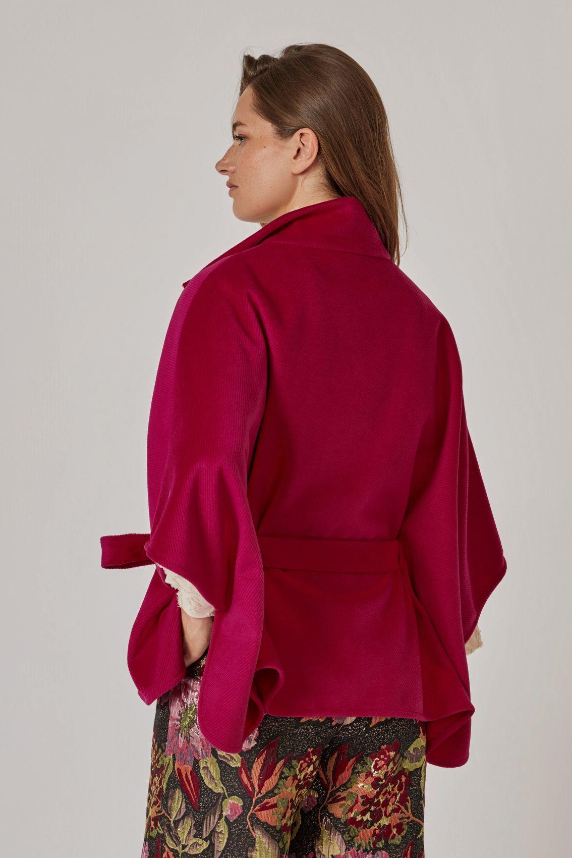 Model trägt Cape Magenta, Rückansicht mit Bindegürtel und weitem Fall. 