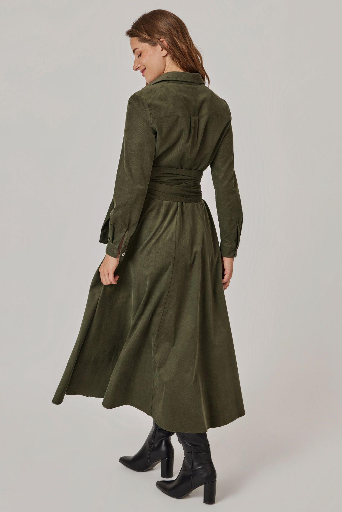 Model trägt olivgrünes Cordkleid, Rückenansicht mit geschwungenem Rockverlauf.