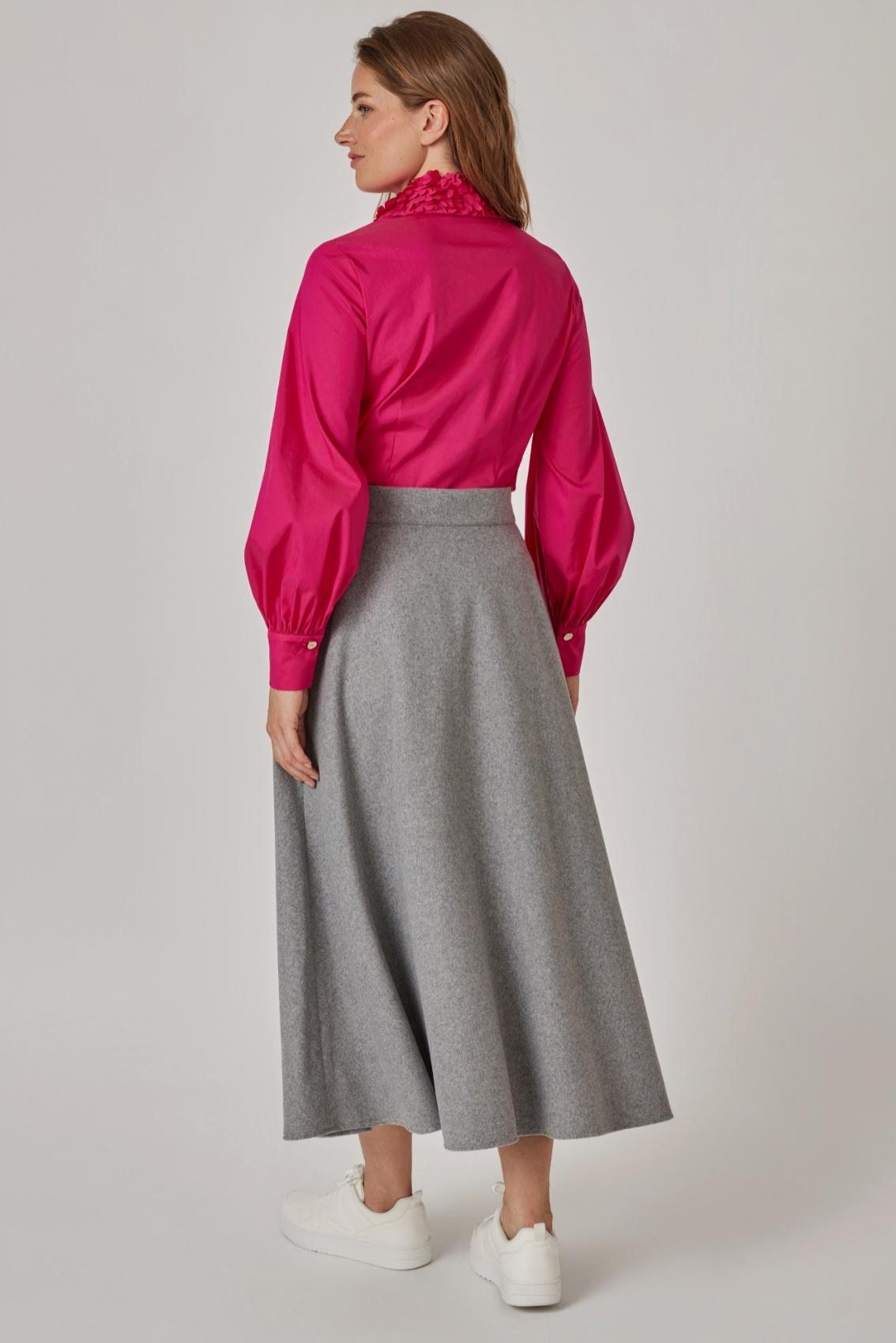 Model trägt grauen Rock in Rückansicht, glatter Bund und weit schwingender Saum, dazu pinke Bluse und weiße Sneaker.