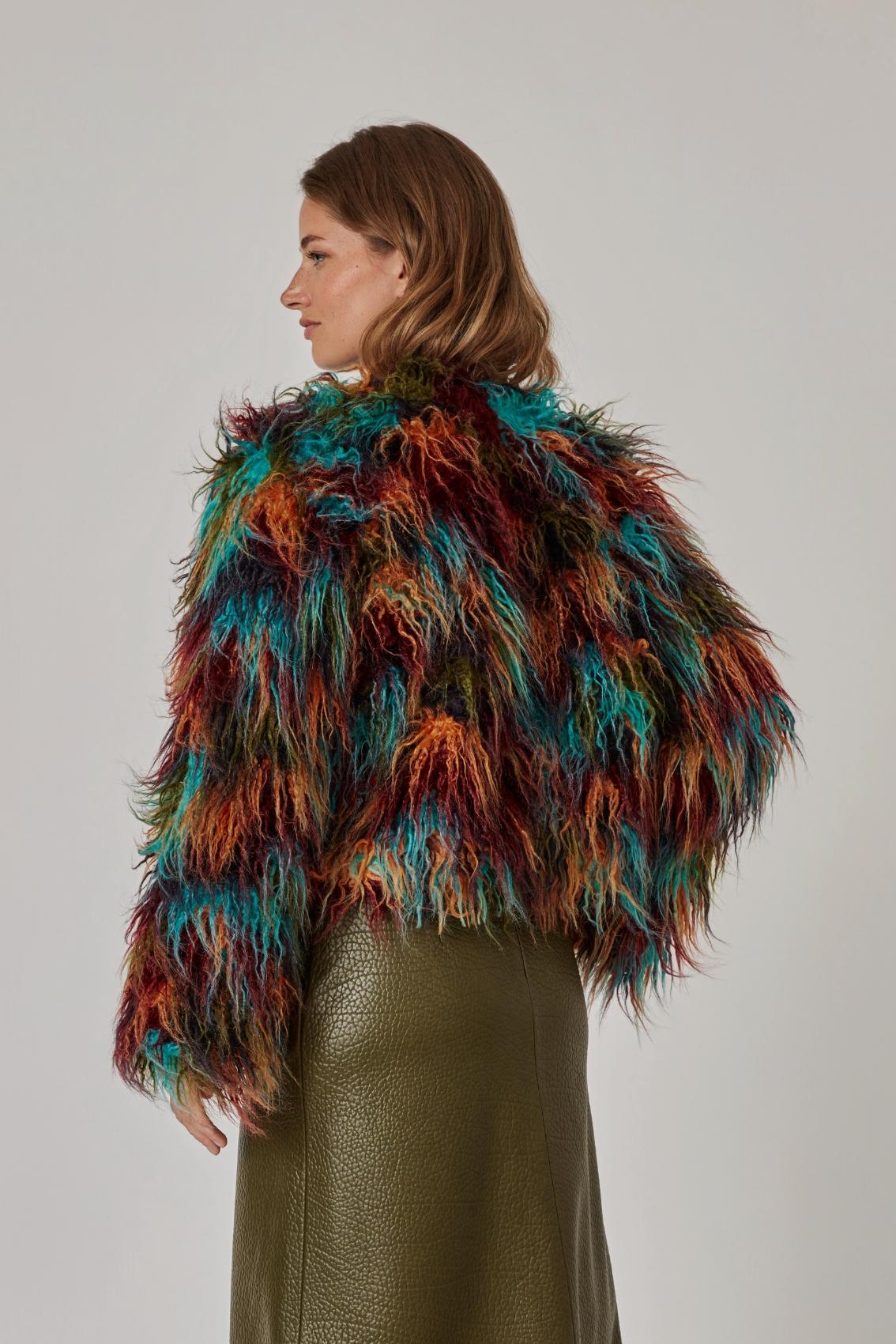 Model trägt Kunstpelzjacke in Türkis, Rost, Bordeaux und Oliv, Rückenansicht mit kurzem, geradem Saum.