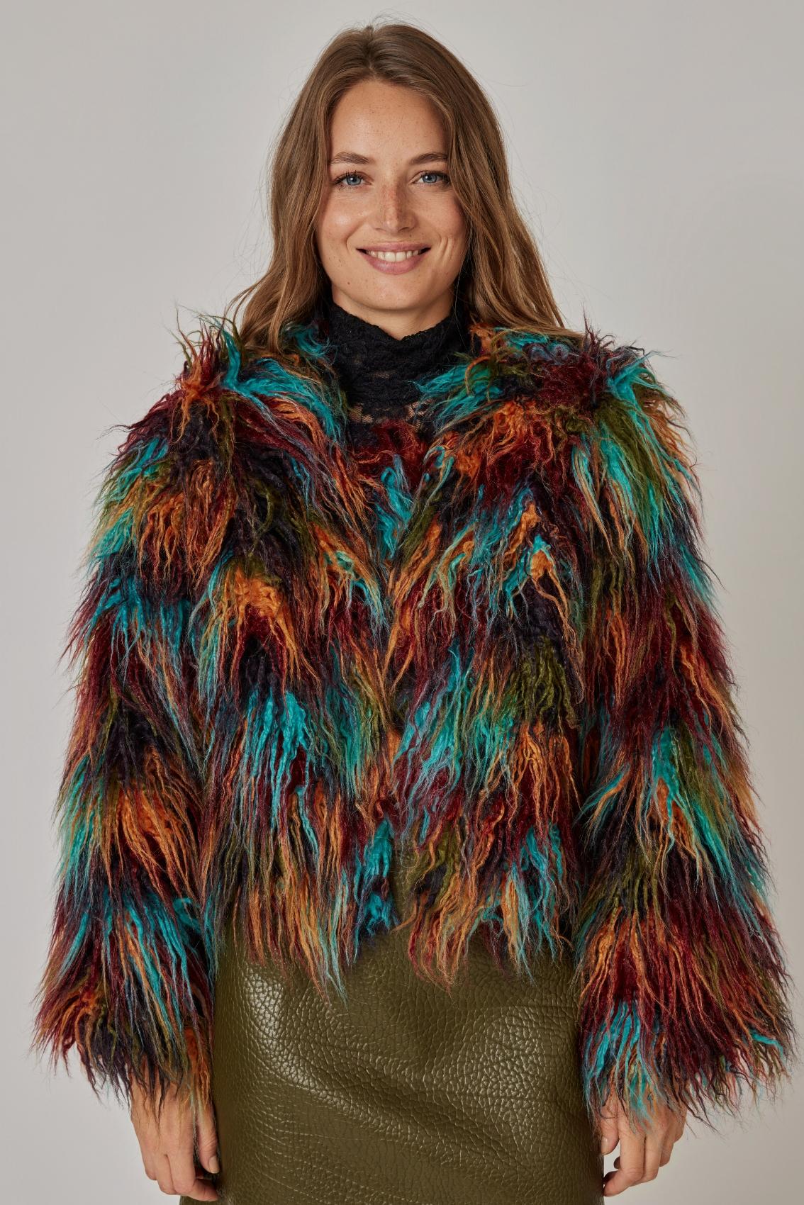Model trägt kurze Kunstfelljacke Multicolor zu schwarzem Spitzenrolli und olivgrünem Rock, Frontansicht.