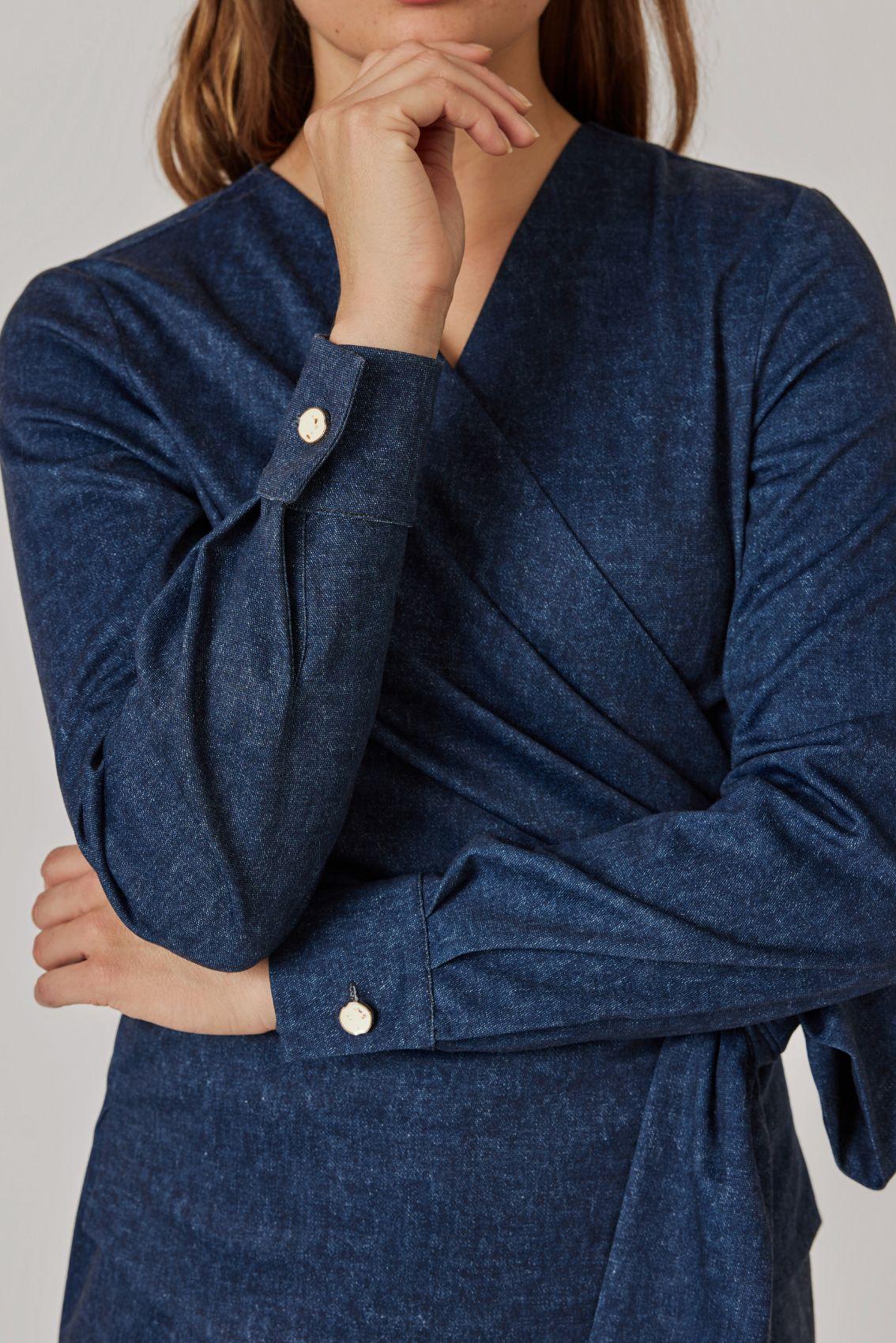 Detailansicht: Manschette mit goldfarbenem Knopf und drapiertem Wickel in Denim-Blau.