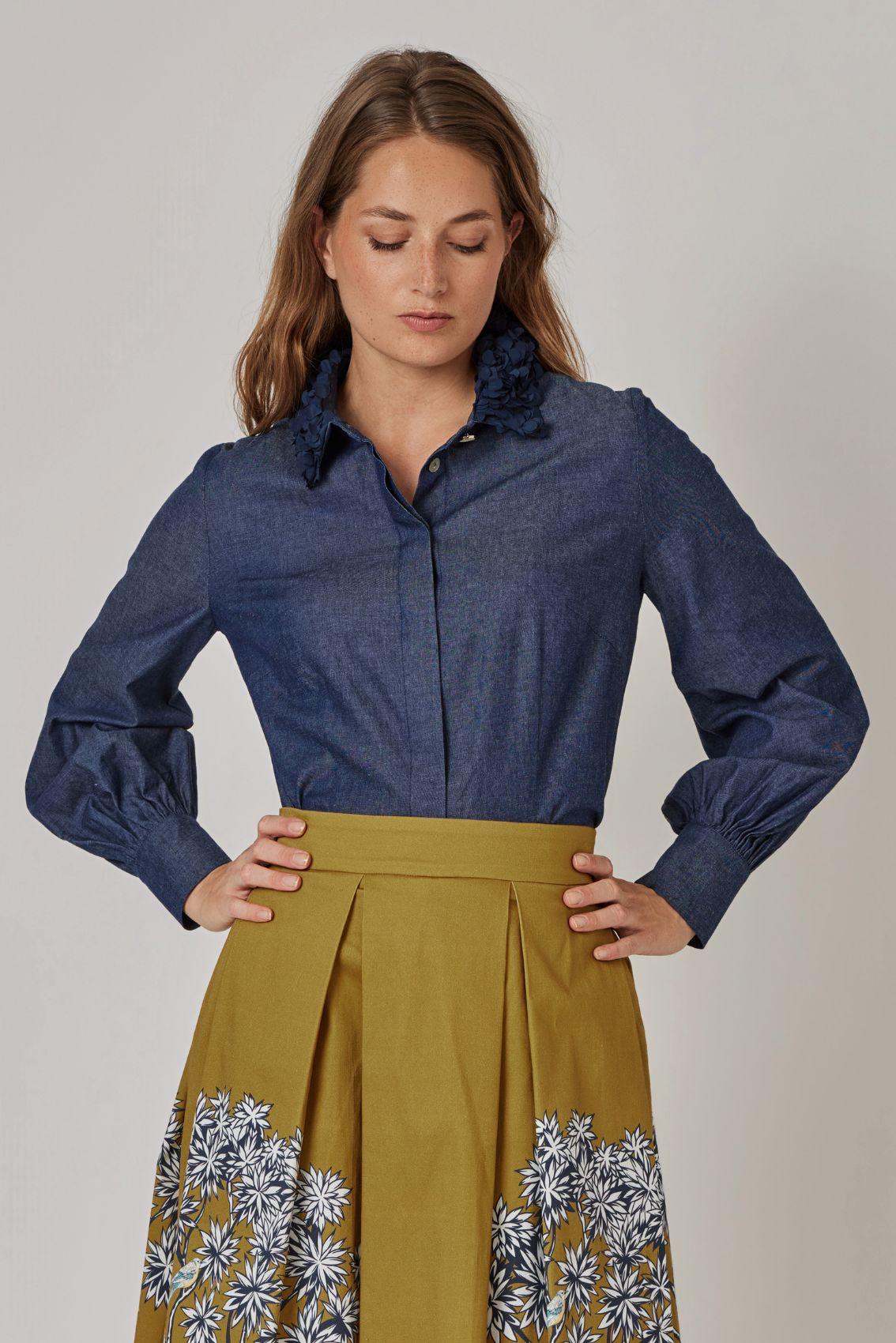 Model trägt denimblaue Bluse mit floralem Kragen, Frontansicht. 