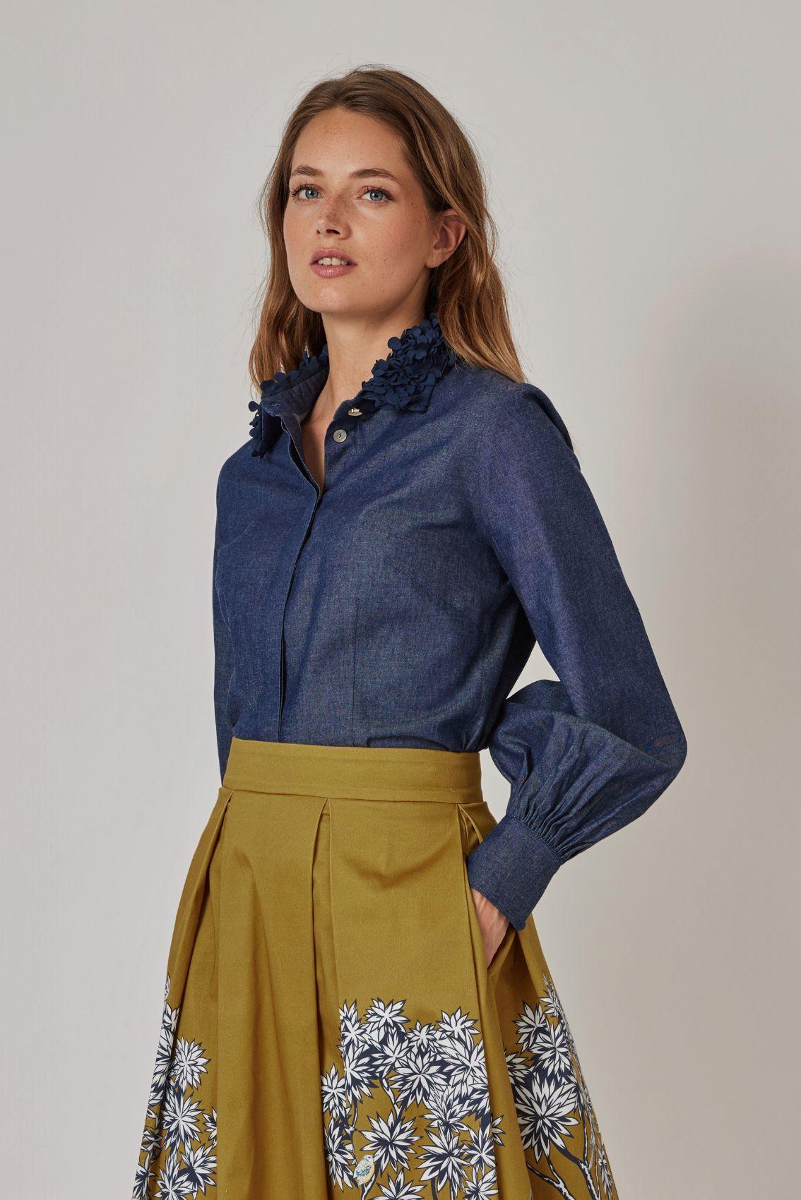 Model trägt taillierte Bluse in Denimblau, Seitenansicht mit Ballonärmel. 