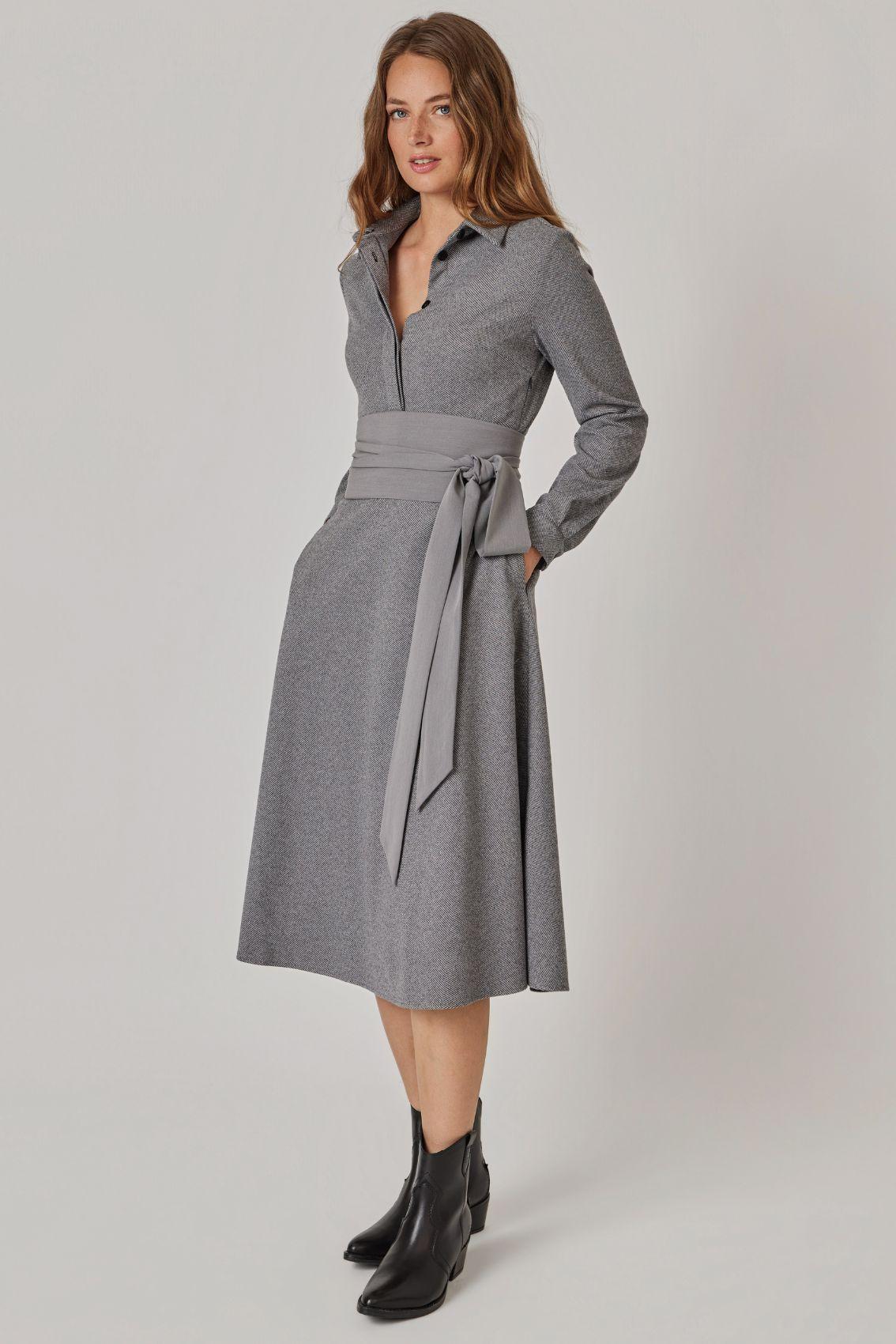 Model trägt Blusenkleid mit Hemdkragen, Bindegürtel und Seitentaschen, Frontansicht.