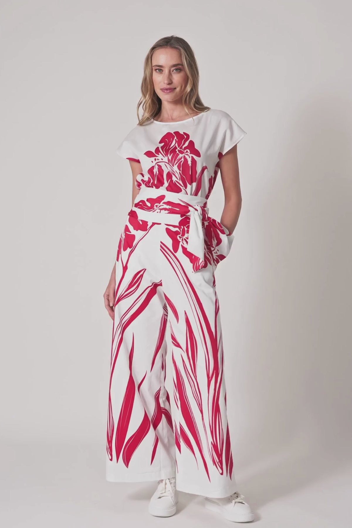 Model trägt weiße High-Waist Hose mit weitem Bein mit rotem Print und hohem Bund.