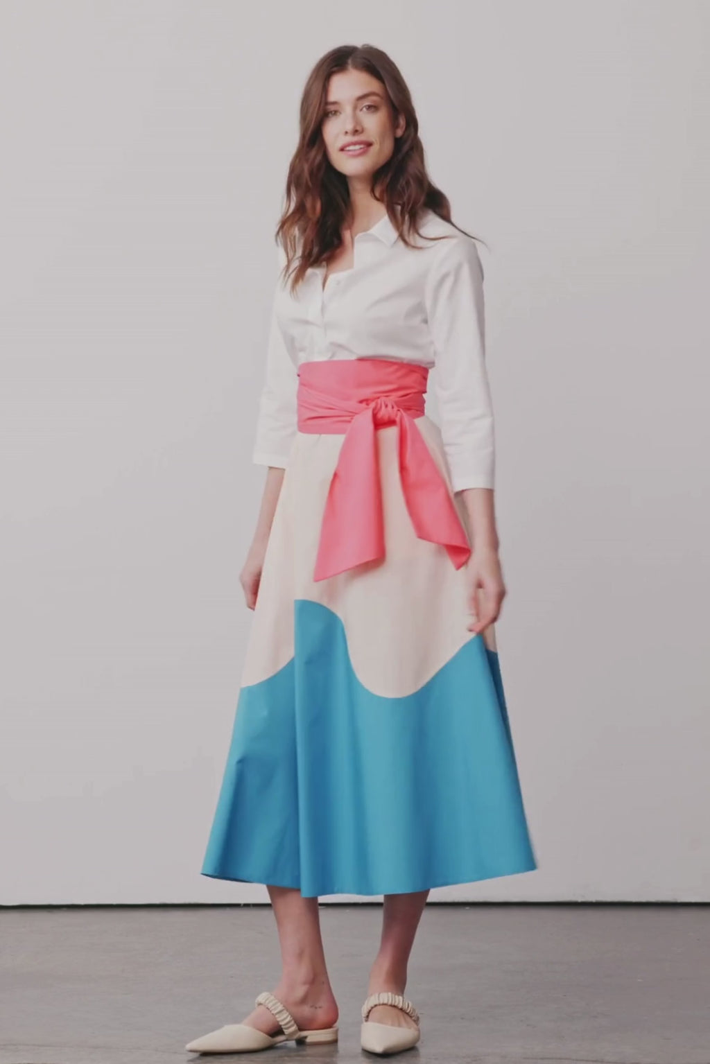 Model dreht sich in einem Blusenkleid mit Colorblock-Farben Rosa, Apricot und Blau