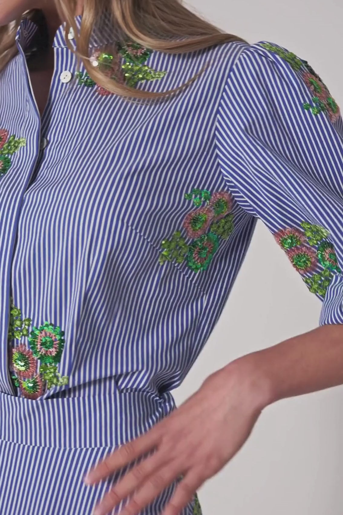 Detailaufnahme der Paillettenblüten auf blau-weißen Streifen der Bluse, Struktur und Schimmer sichtbar.