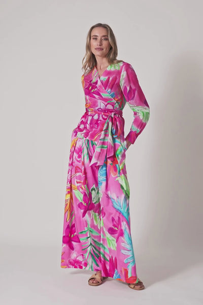 Model trägt pinke, weit geschnittene Hose mit floralem Print und hohem Bindegürtel. 