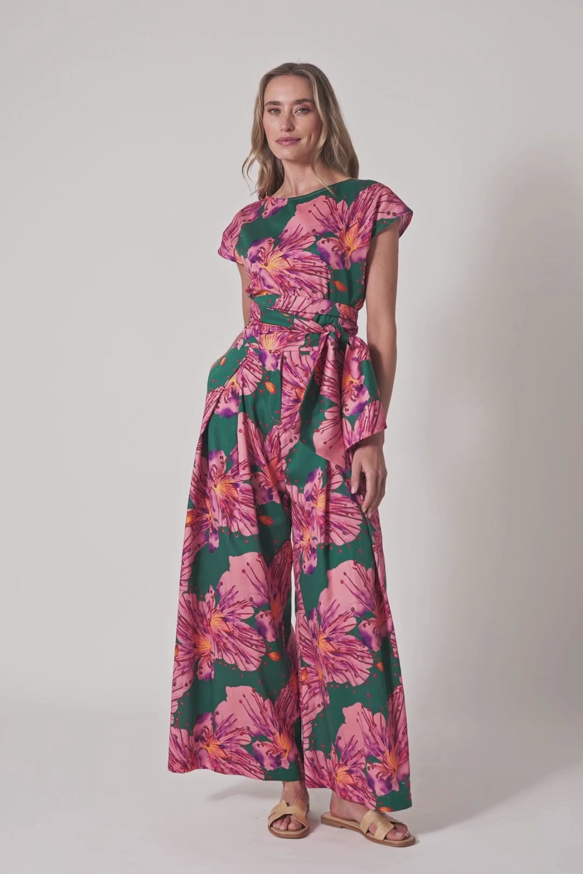 Model trägt grüne, weite Hose mit floralem Print und Bindegürtel.