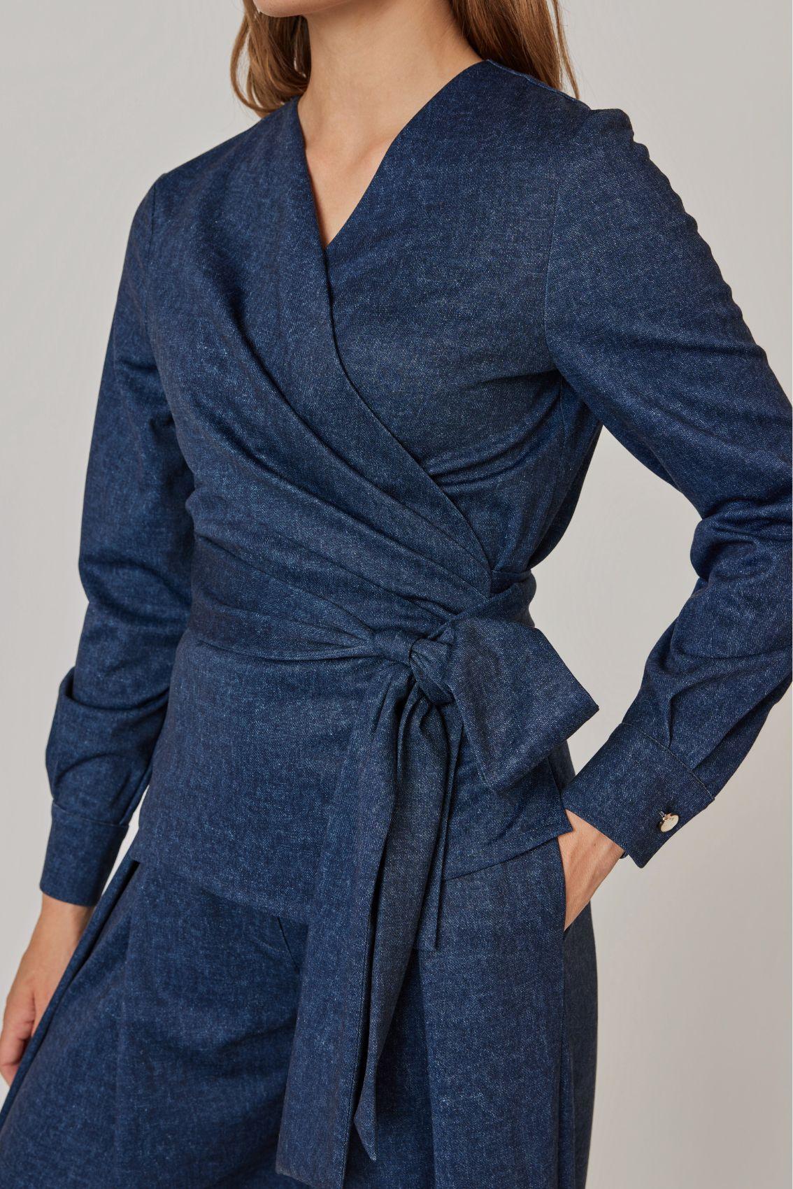 Model trägt Bluse in Denim-Blau mit seitlich gebundener Schleife und langen Bändern, Seitenansicht.