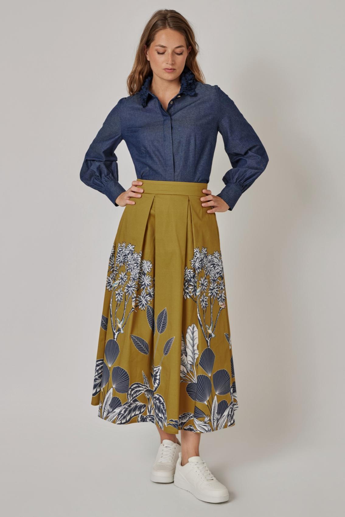 Model trägt Senf-farbenen Maxirock mit Botanikdruck, Frontansicht, kombiniert mit Denimbluse. 