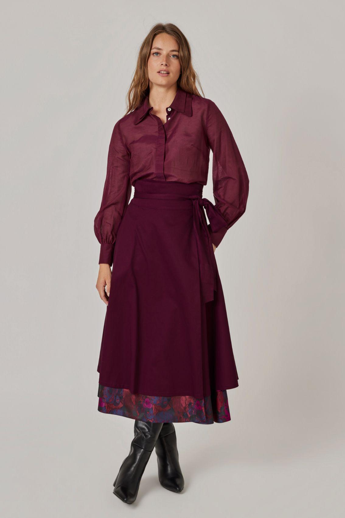 Model trägt Wickelrock gewendet in Aubergine mit Bindegürtel, am Saum ist das Rosen-Jacquard sichtbar, Frontansicht.